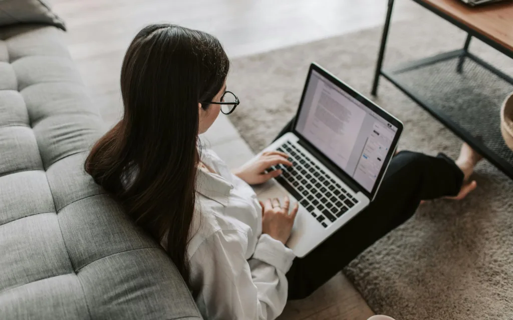 Studentka pracuj e na laptopie oparta o kanapę