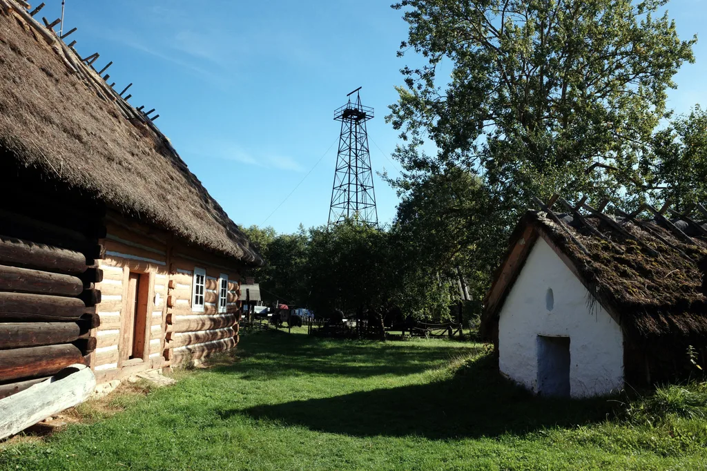 Drewniane chałupy i wieża wiertnicza w skansenie w Sanoku