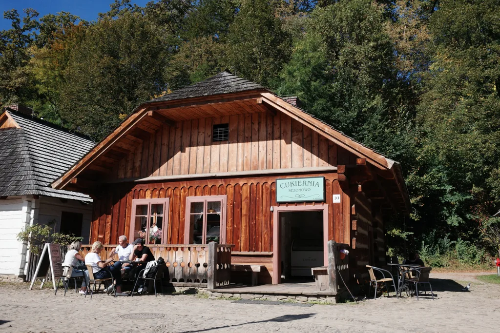 Cukiernia w skansenie w Sanoku przed którą przy stoliku siedzą turyści